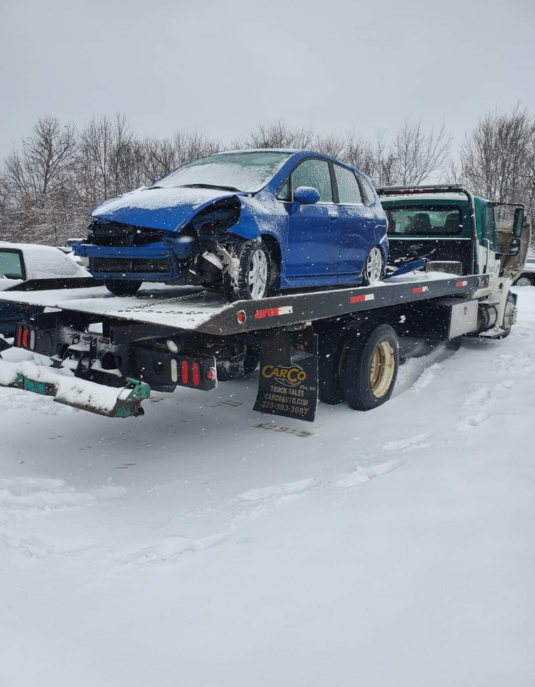 Chuck's Towing, serving the Joplin, Carthae, Webb City and surrounding areas, hauling a blue sedan on a snowy day.